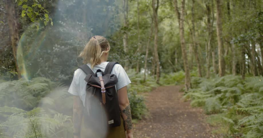 A woman is hiking through a forest during the day