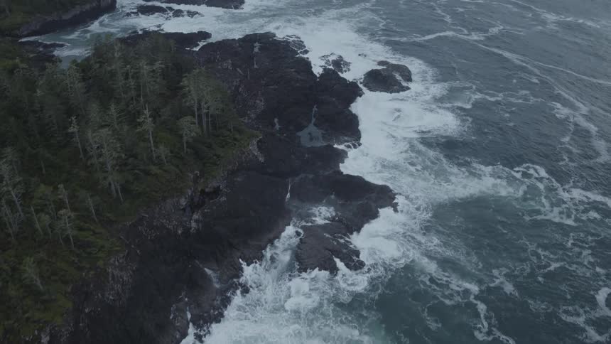 Aerial shot of a rocky coastline as waves crash from the ocean