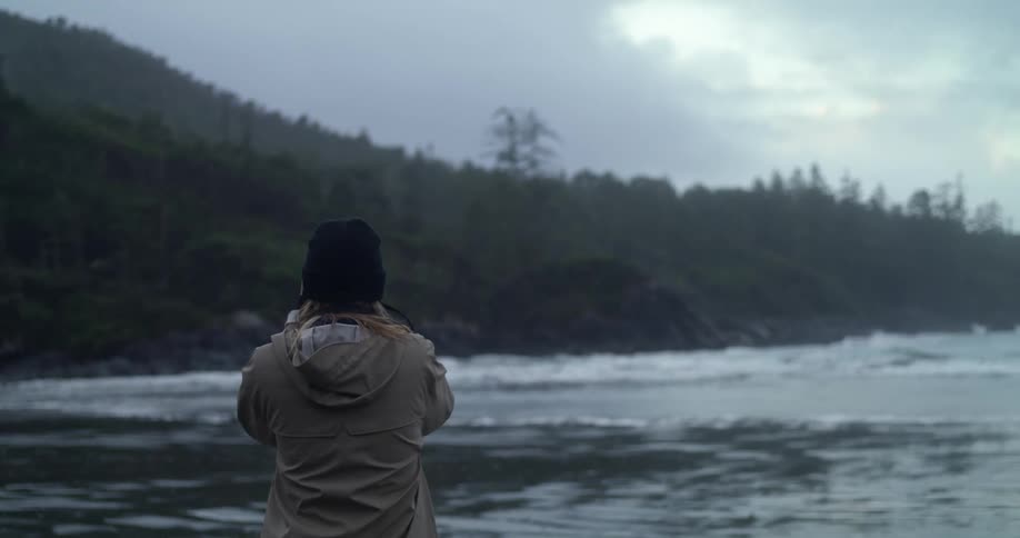 Woman taking photos of the ocean and stormy coast
