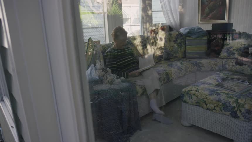 A woman is sitting on a couch reading a book