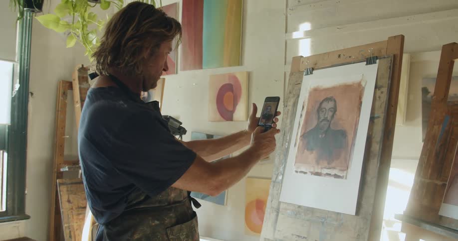 A man taking a photo of his painting