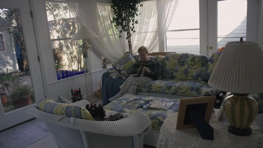 A woman sits on a sofa while reading