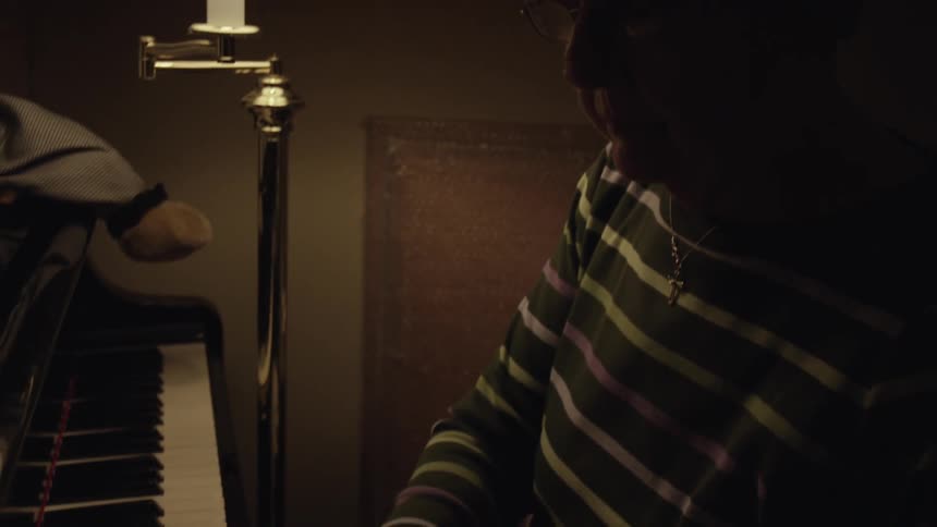 A woman in a striped shirt plays the piano