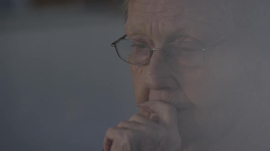 An old woman in thought with her hand up to her face