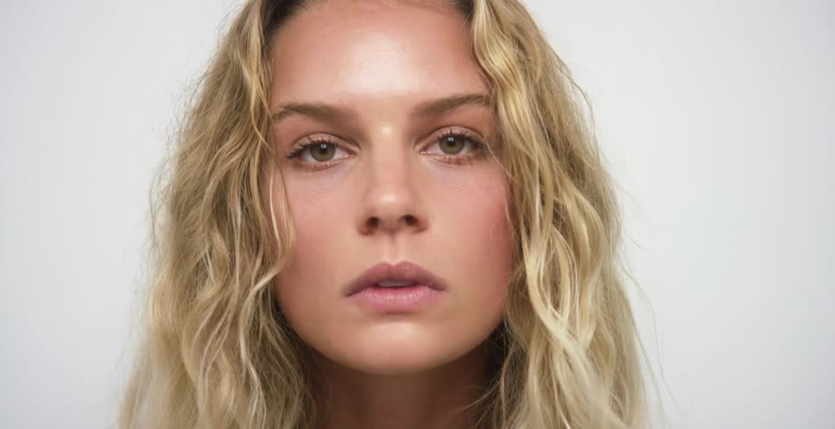A woman with long blonde wavy hair looks up