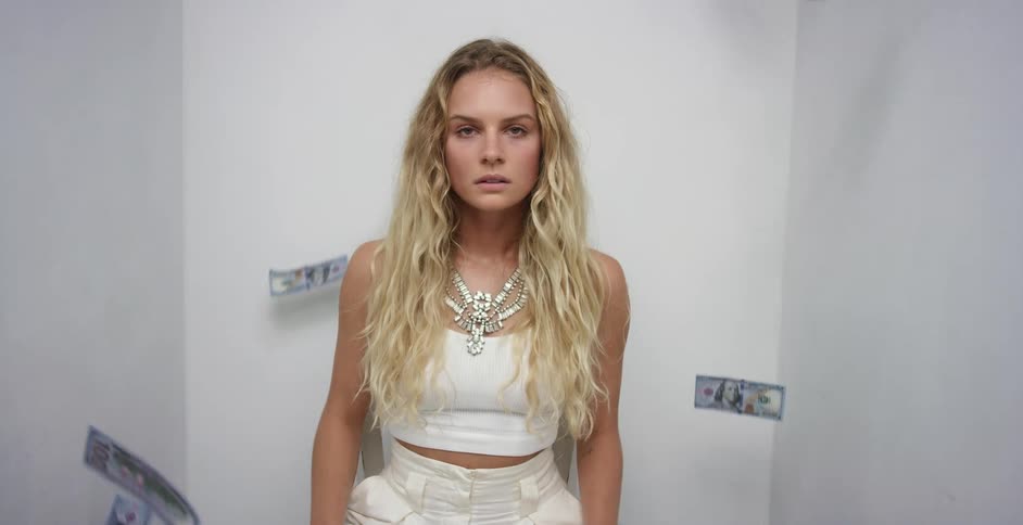 A woman standing and staring in a room with money falling