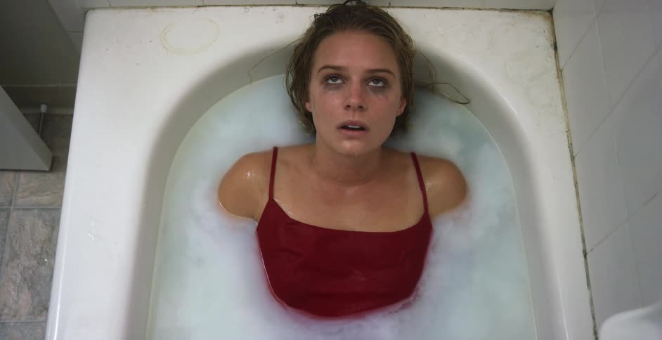 Sad depressed woman in a red dress inside a bathtub at home