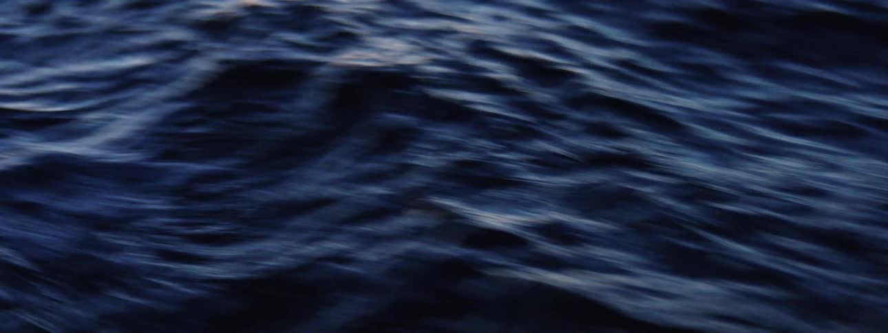 Small waves ripple in deep blue ocean water