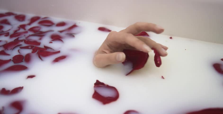 Woman taking a bath in a bathtub with red rose petals