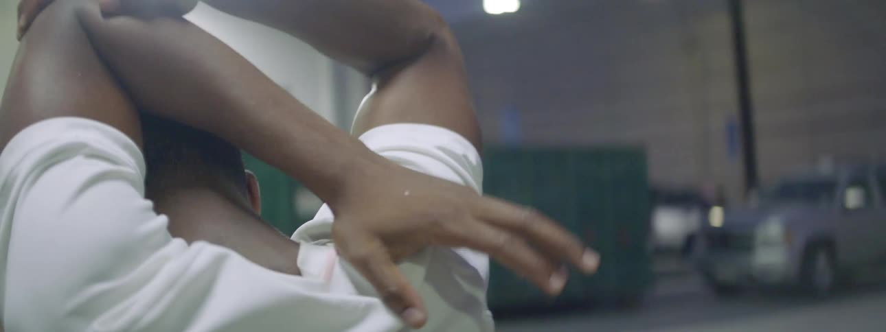 A man stretching his arms while walking in a parking garage