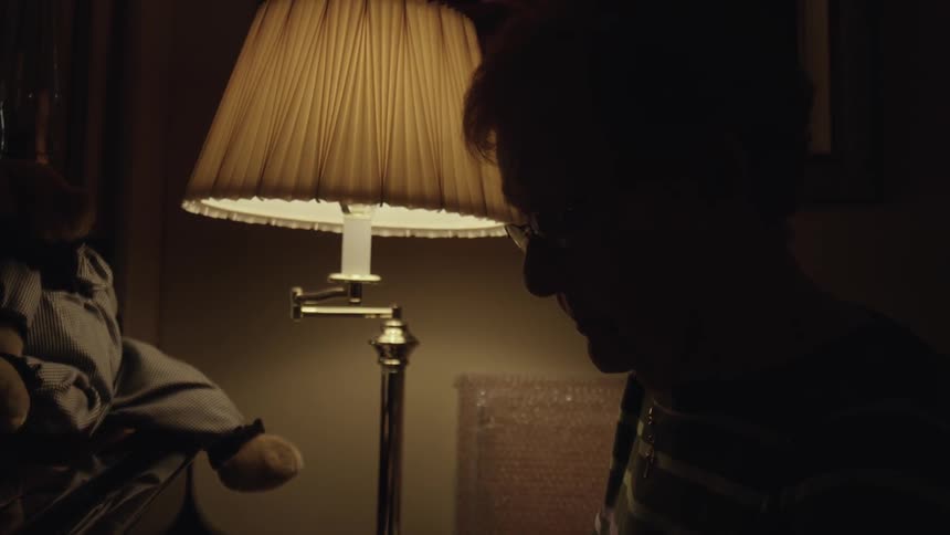 A person is sitting down next to a lamp in a dark room