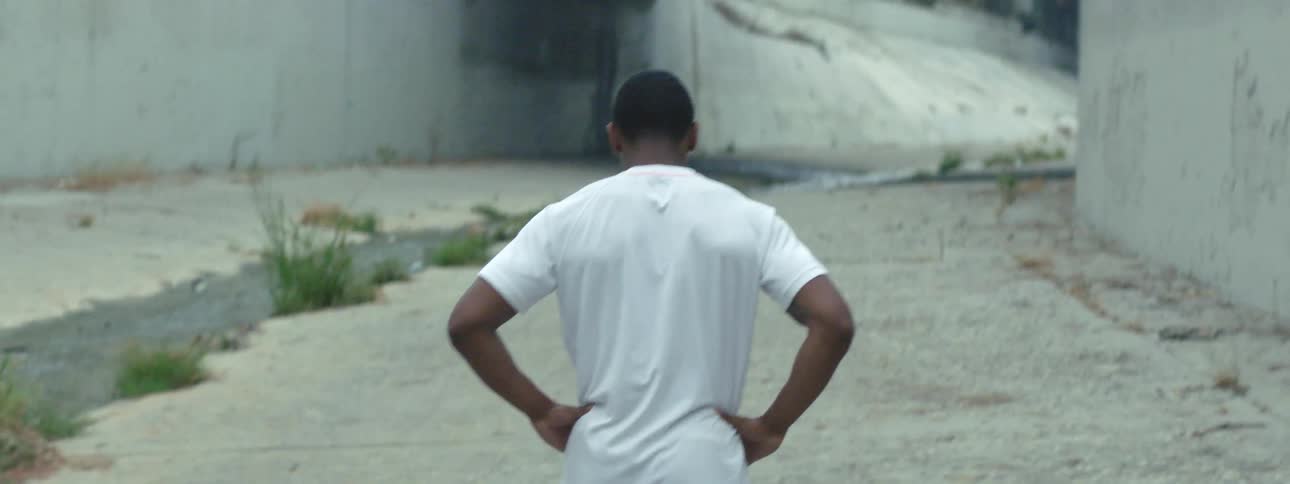 A man in a white tee shirt jogging outside in a concrete canal