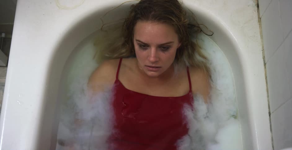 A woman lies in a bathtub being filled with white liquid