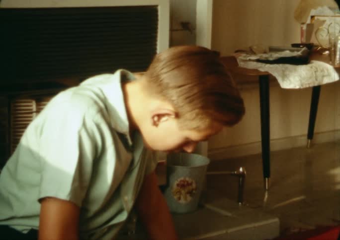 A boy sitting in a living room looking down at a magazine