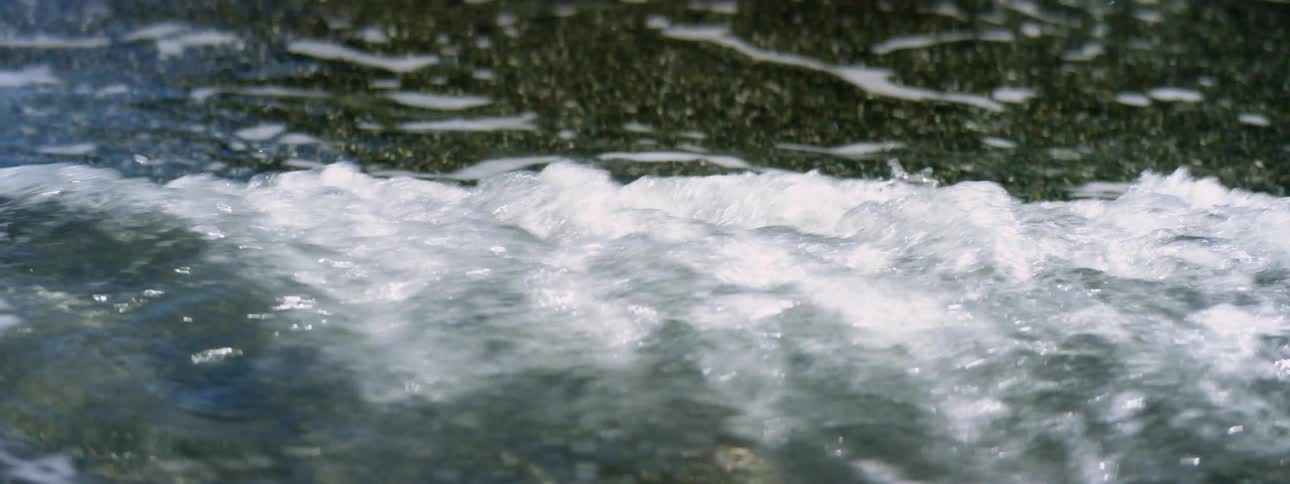 Waves of clear water washing over the black pebbles in a beach coastline