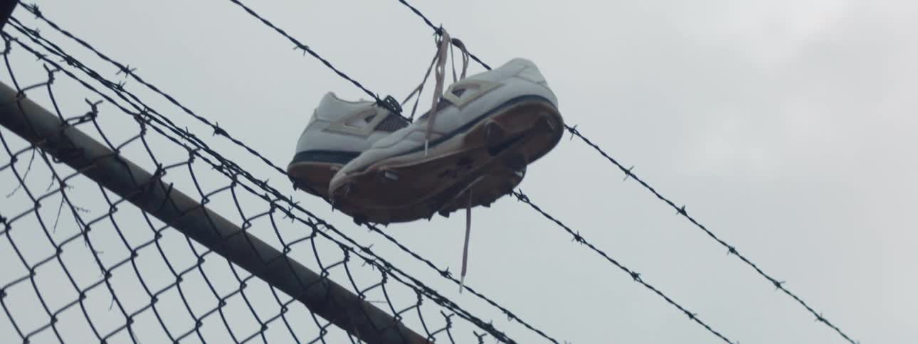 White shoes hanging on barbed wire over a fence