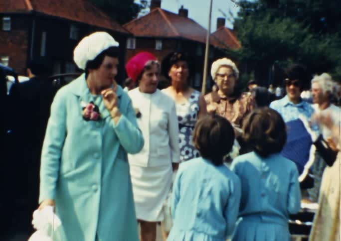 Vintage film of a family gathering outside a venue in formal dress