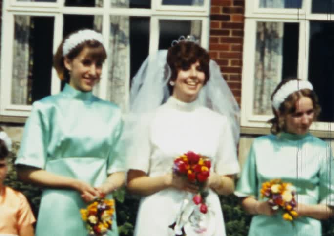 Bride and bridesmaids posing for a picture outside a house on vintage film