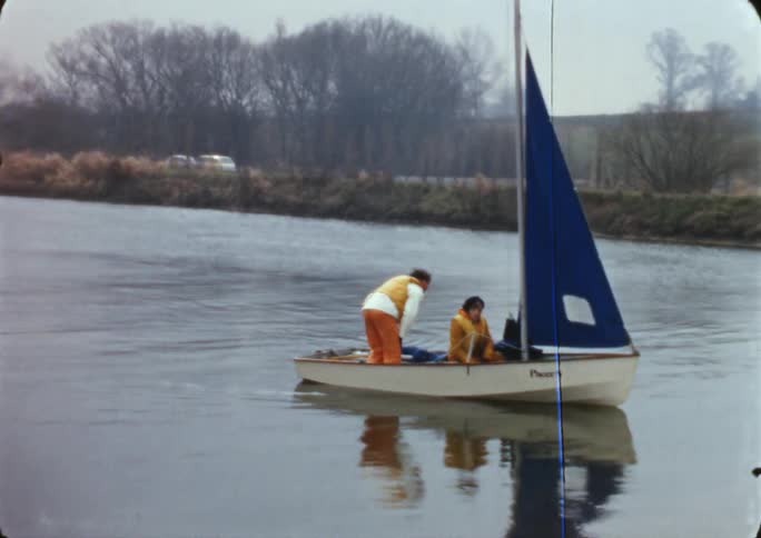 People on a tiny sail boat in a river bed