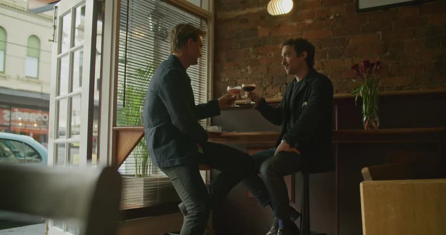 Two men drinking cocktails at the bar and cheering