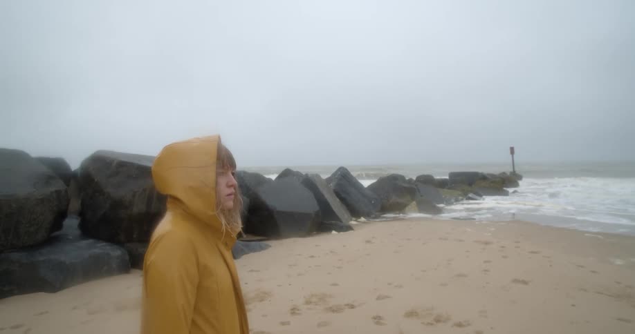 A woman walking down a windy beach