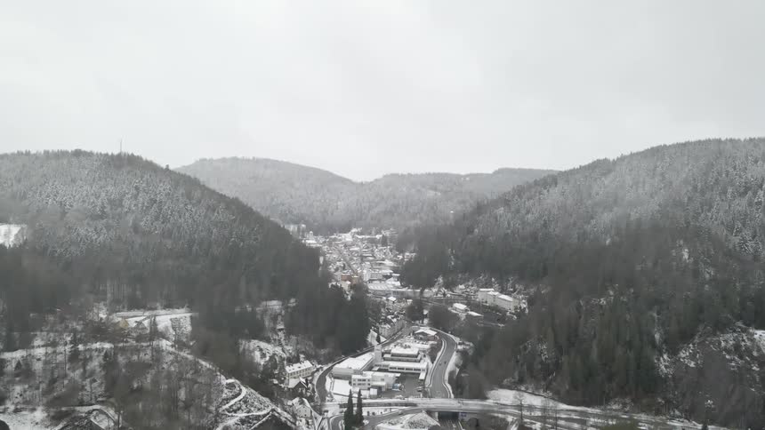 A town in a valley covered in snow with a mountain range the sky and clouds in the background