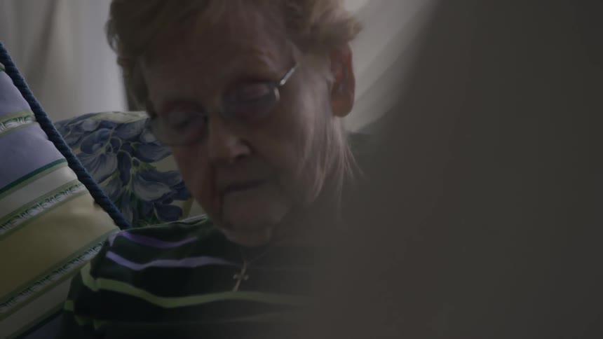 An older woman sits on a sofa and reads