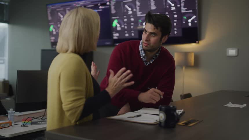 Two coworkers talking on a desk in an office