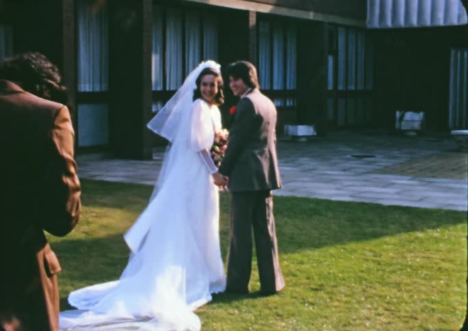 A woman in a wedding dress and a man in a suit standing and holding hands