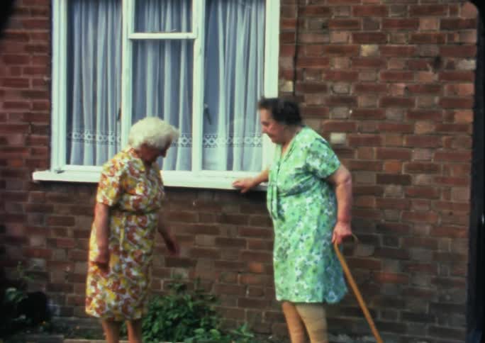 Women walking and standing in front of a house