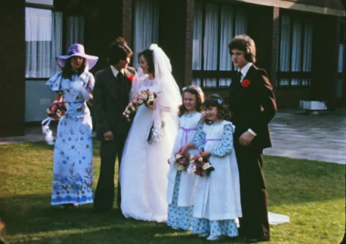 Young groom and bride pose for a picture in the lawn outdoors