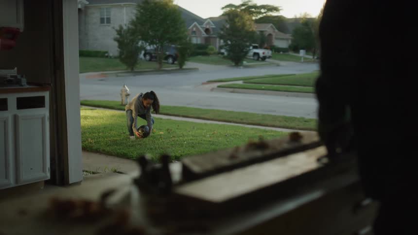 A man doing carpentry work in his garage stops and waves at a little neighbor girl