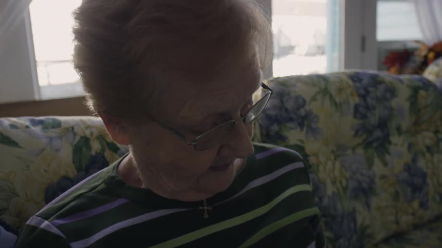 A woman is looking down as she sits on a couch