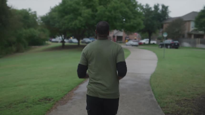 Man jogs along path toward parking lot next to apartments
