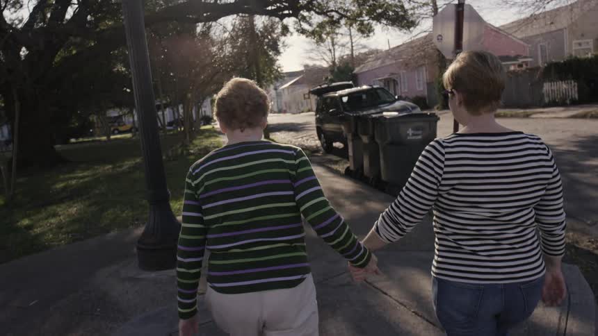 Two women walk down a residential street while holding hands