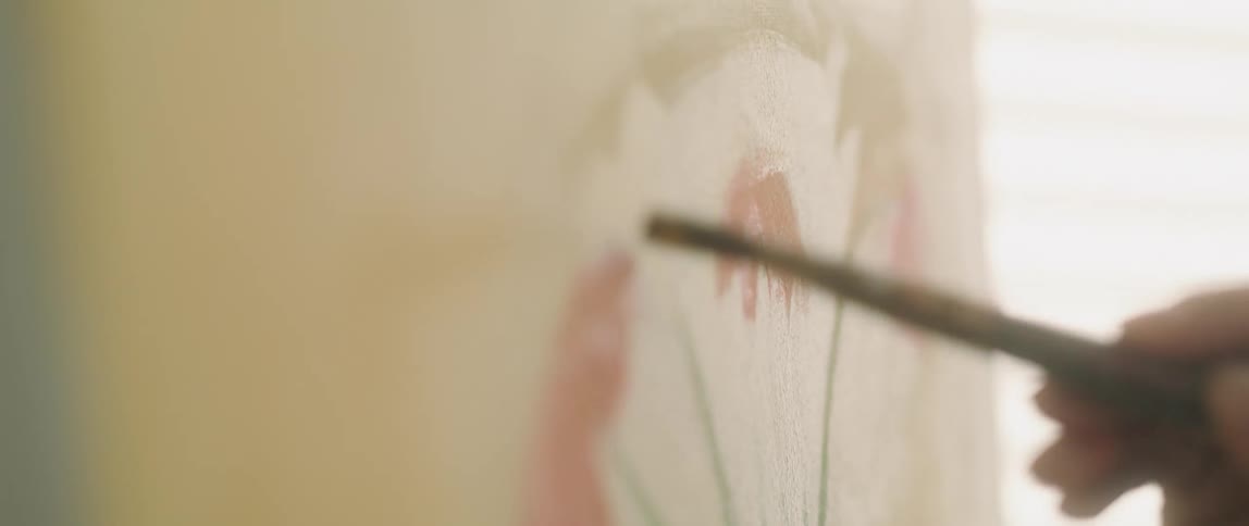 Painter uses a brush to paint a vase with oils over canvas in a room