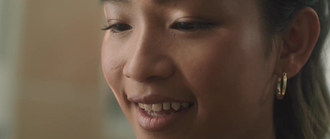 A teenage girl stands indoors and is smiling