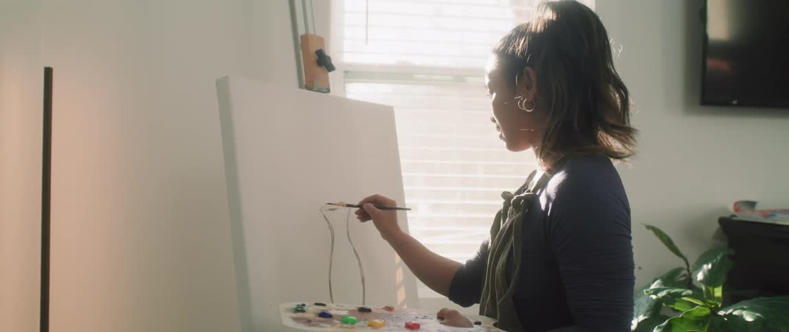 A teenage girl painting a picture at home