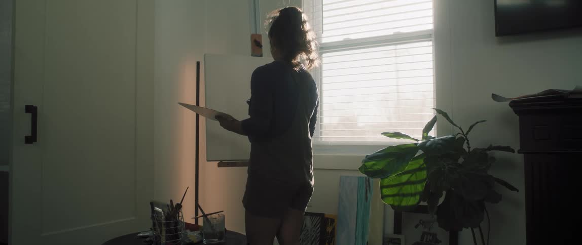 Woman painting a canvas next to window