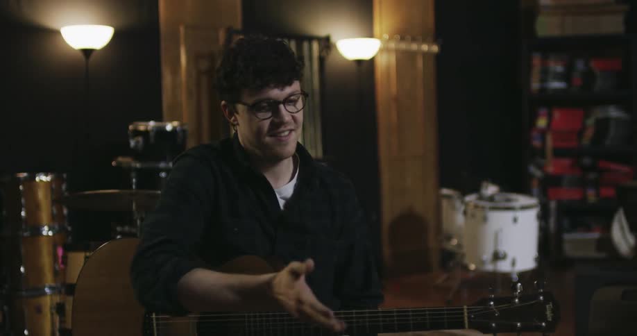 A man picks up a guitar and sits down