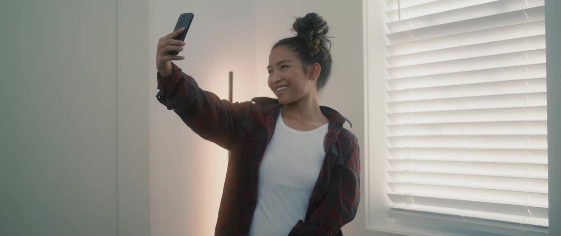 A young woman taking selfies inside of a bedroom at daytime