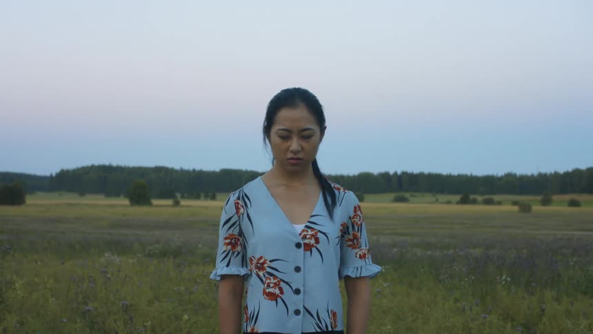An asian woman stands in a field outside showing different expression of sadness screaming and anger