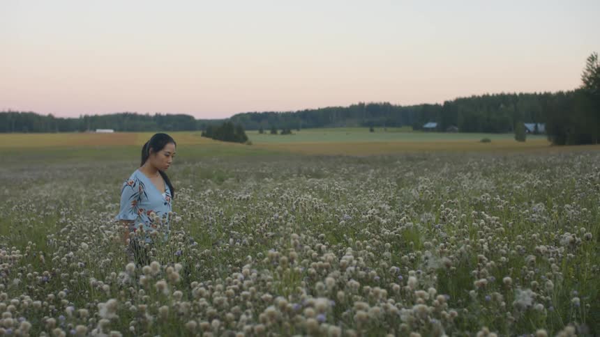 Woman walking through a field of flowers in the countryside during the day