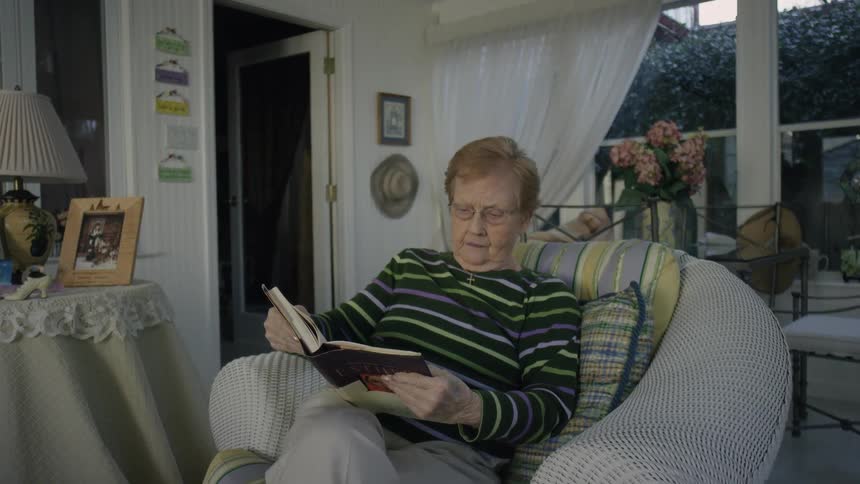 A woman is sitting down in a chair reading a book