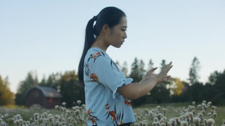 A woman is standing outdoors at dusk