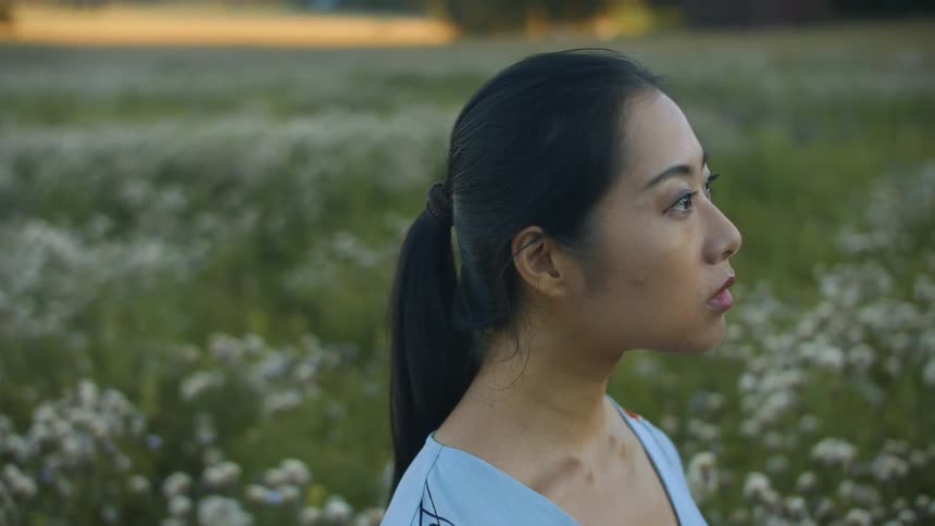 A woman stands in a field and looks into the distance