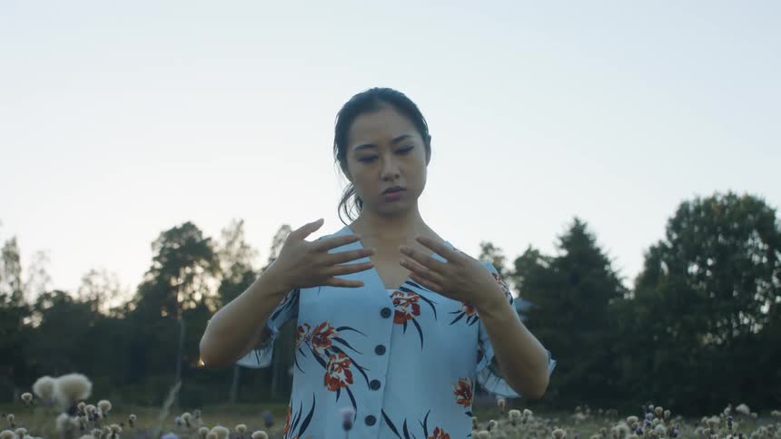 Woman standing out in a flower field practicing spiritual dance