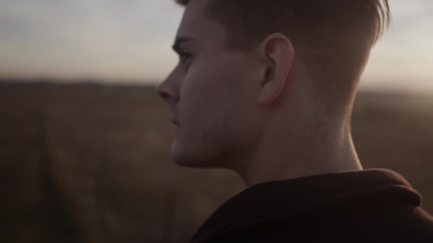A man stares into the distance at sunrise