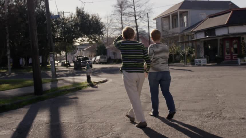 Two women walk across the street holding hands