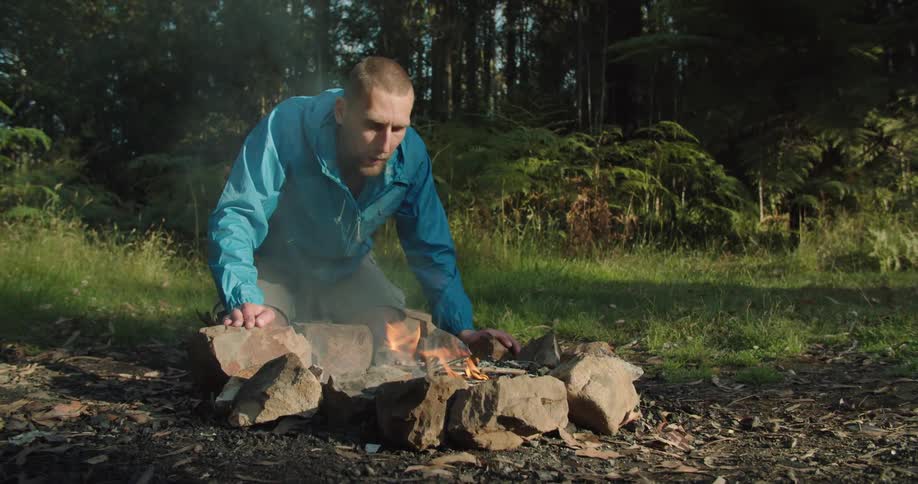 Man blowing a bonfire in the middle of the forest
